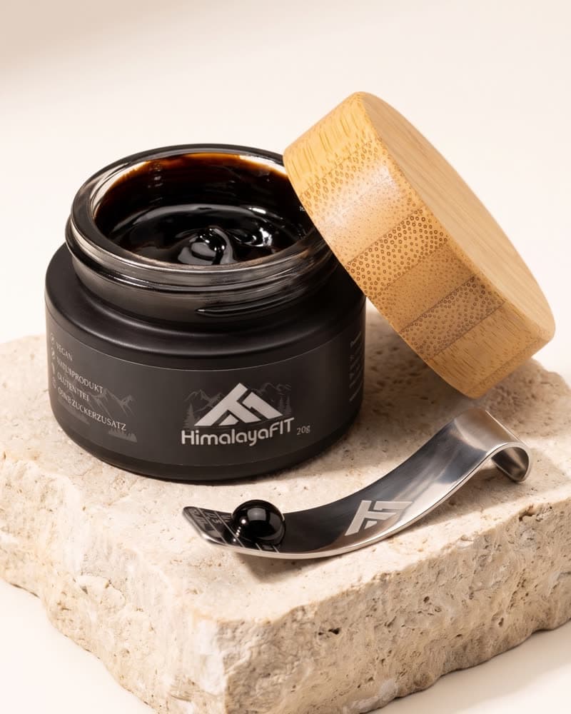Geöffneter HimalayaFIT Tiegel mit Shilajit-Harz und Dosierlöffel auf einem Stein