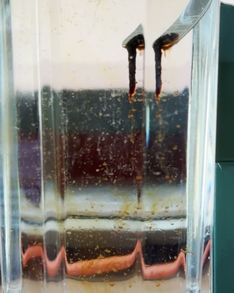 Shilajit-Harz am Löffel löst sich in einem Glas Wasser