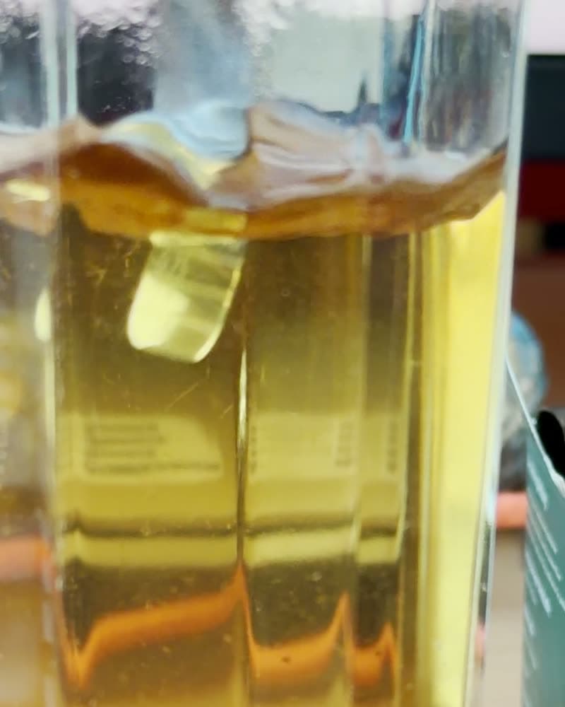 Löffel rührt Shilajit in ein Glas Wasser, das sich bernsteinfarben färbt