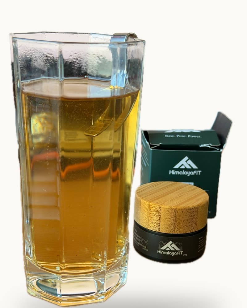 Glas mit aufgelöstem Shilajit neben HimalayaFIT Tiegel und Verpackung
